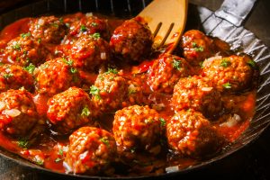 Delicious meatballs made from ground beef in a spicy tomato sauce served in a skillet or old metal pan in a restaurant